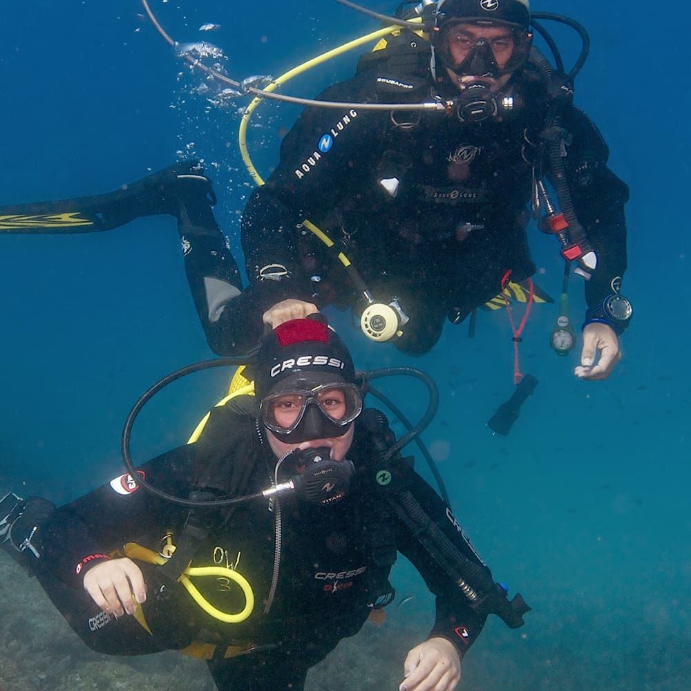 Un bautismo bajo el agua: delante, quien bucea por primera vez con el jacket amarillo del centro; detrás, el instructor.